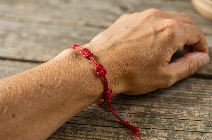 Gros plan d'un bracelet fil rouge à 7 nœuds porté au poignet d'une femme, symbolisant protection et spiritualité